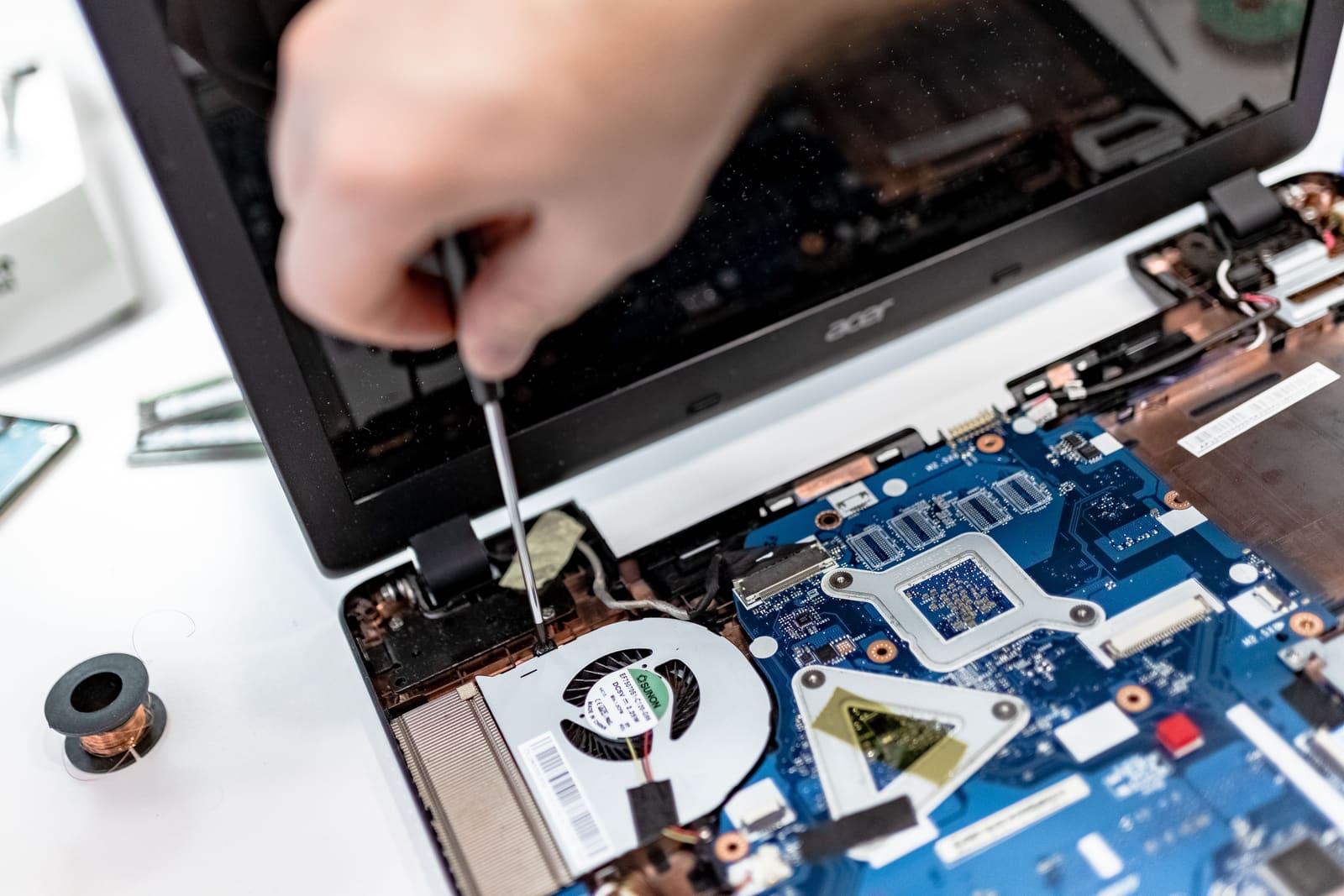 A technician working on the inside of a laptop with a screwdriver