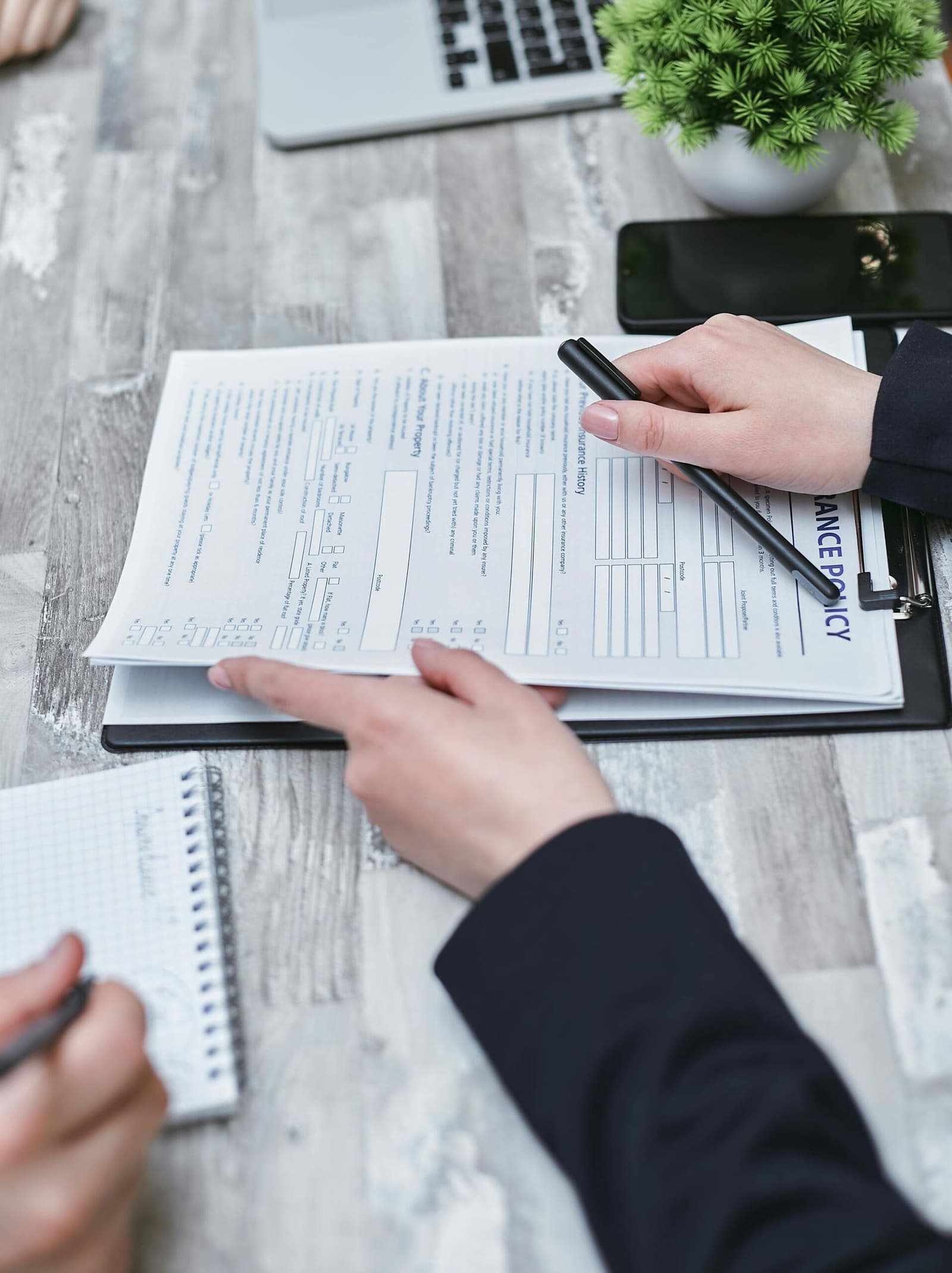Close-up of hands reviewing insurance policy paperwork with a pen on the table